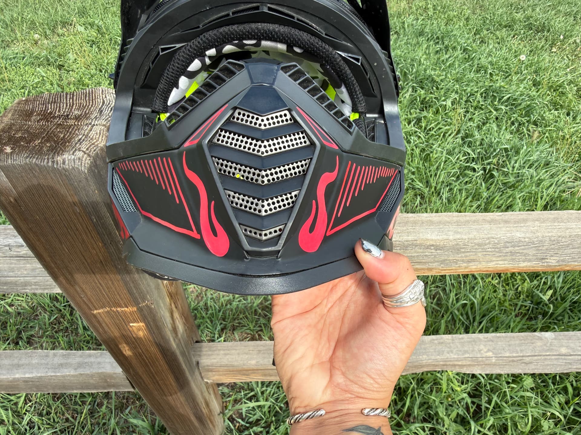 Close-up of pink hand-painted flame detail on the chin bar of a black motocross helmet