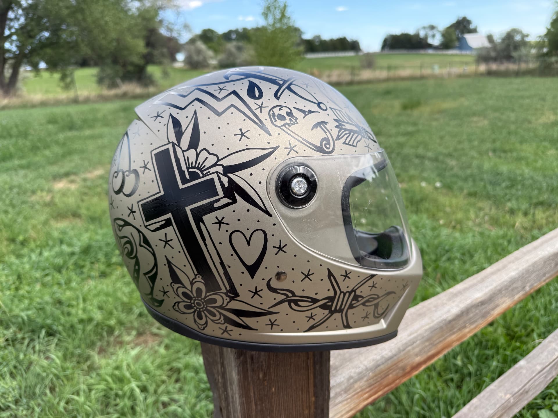 Helmet side painted with a cross, flowers and barbed wire flash