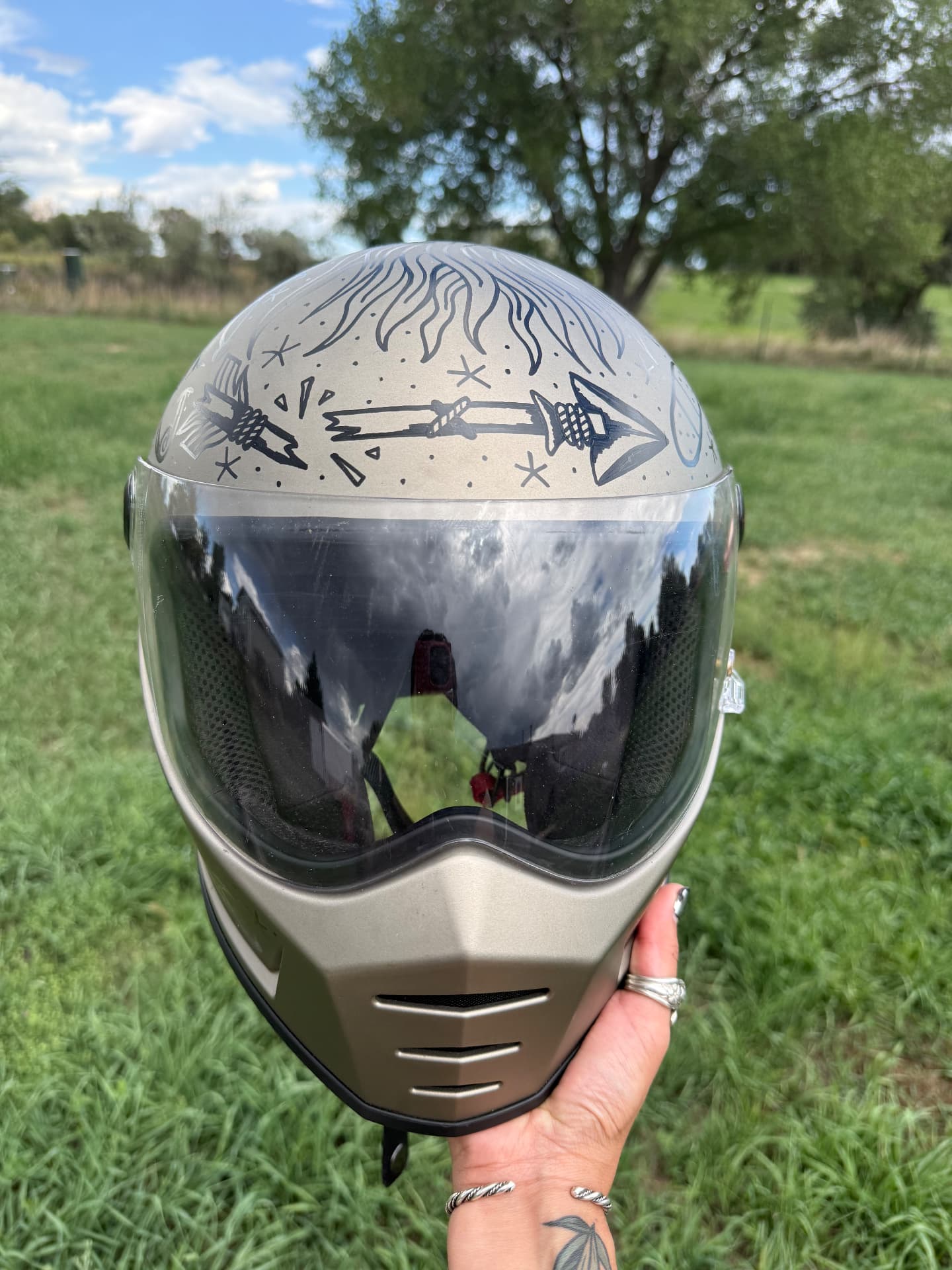 Front of a hand-painted full-face helmet with arrows and flames across the brow