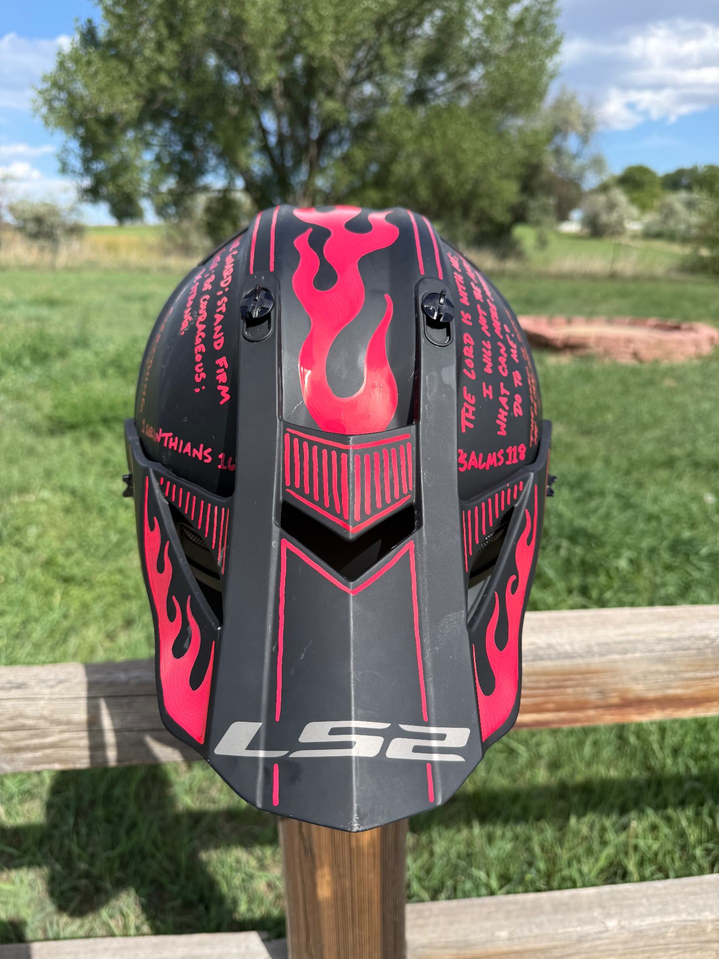 Top view of a black motocross helmet with pink flames and hand-lettered scripture