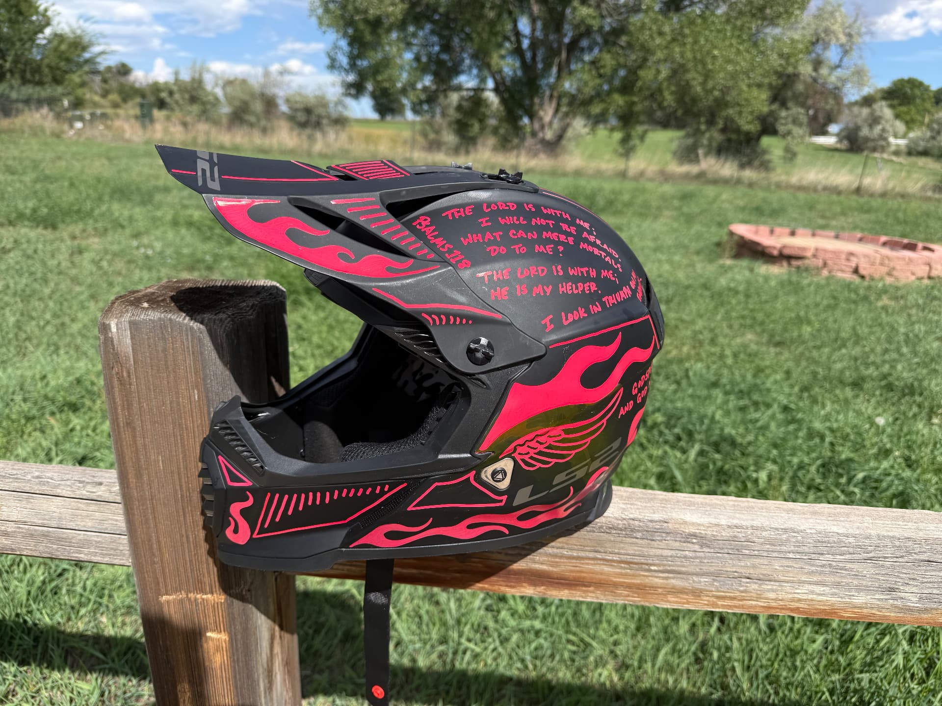Matte black LS2 motocross helmet with hot pink hand-painted flames and scripture lettering